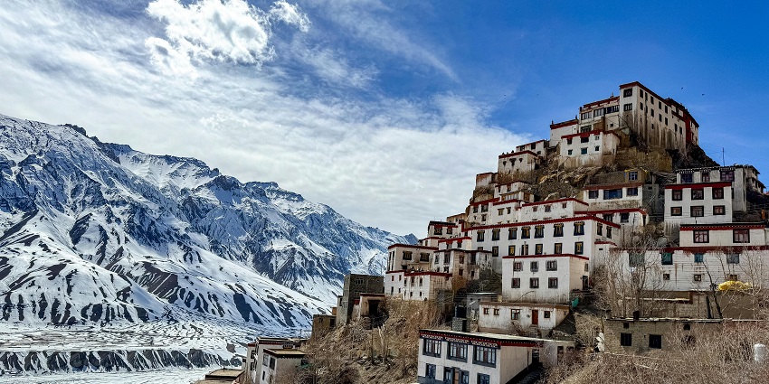 A stunning view of a gompa in Himachal Pradesh with snow-capped mountains behind.