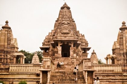 A landscape view of Lakshmana Temple with people sitting on the pavements and around the temple.