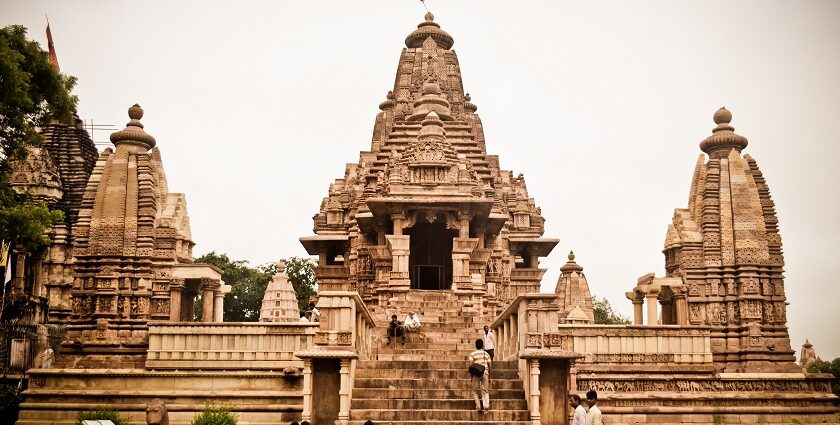 A landscape view of Lakshmana Temple with people sitting on the pavements and around the temple.