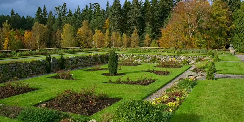 An image of a garden with manicured lawns, colourful flowers, and stone pathways.
