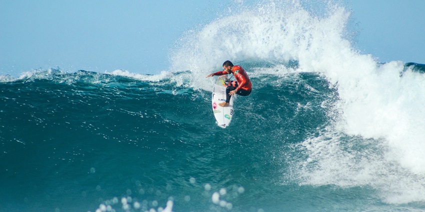 A breathtaking view of a person enjoying surfing on high tides on an ocean in the day.