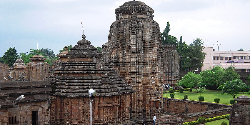 View of an ancient holy shrine surrounded by lush greenery and a background of clear sky.