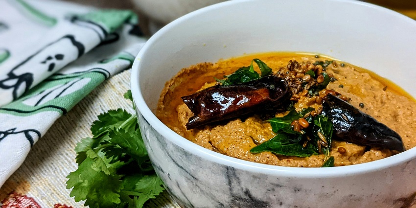 A picture of a ceramic plate with a curry in it, placed on a table with a design printed on the bowl