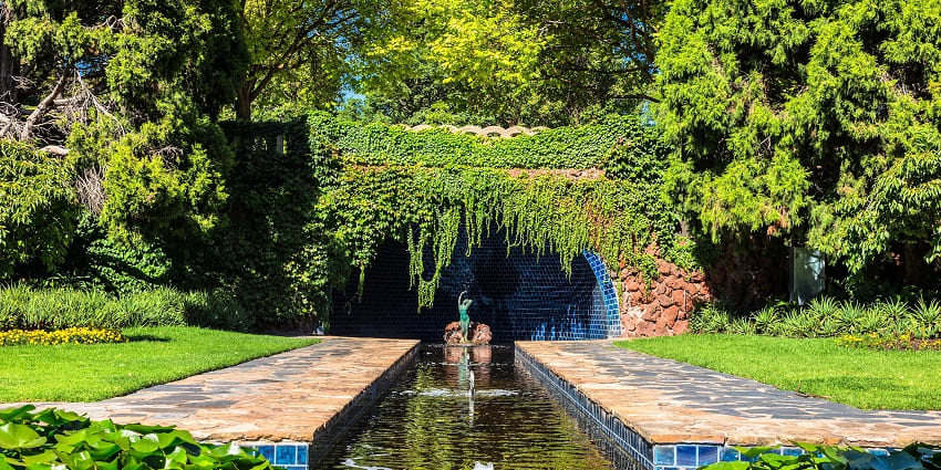 The entrance of Victoria Nature Park, with a water stream surrounded by lush plants