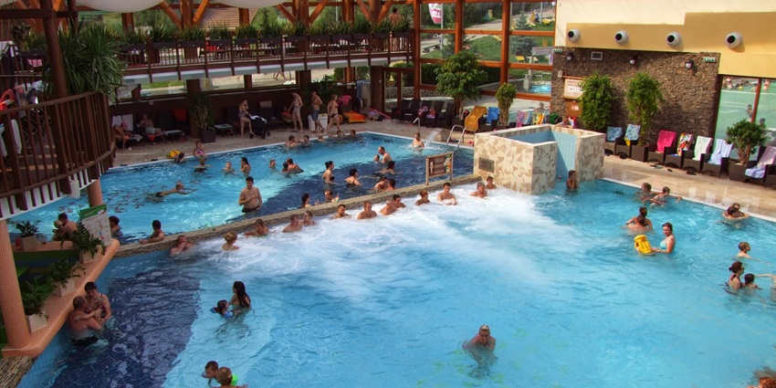 Snapshot from the inside of the water park where visitors are relaxing in the pool under the shed
