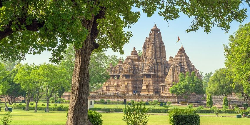 A far view of a tourist attraction Lakshmana temple with a lush garden at the front.