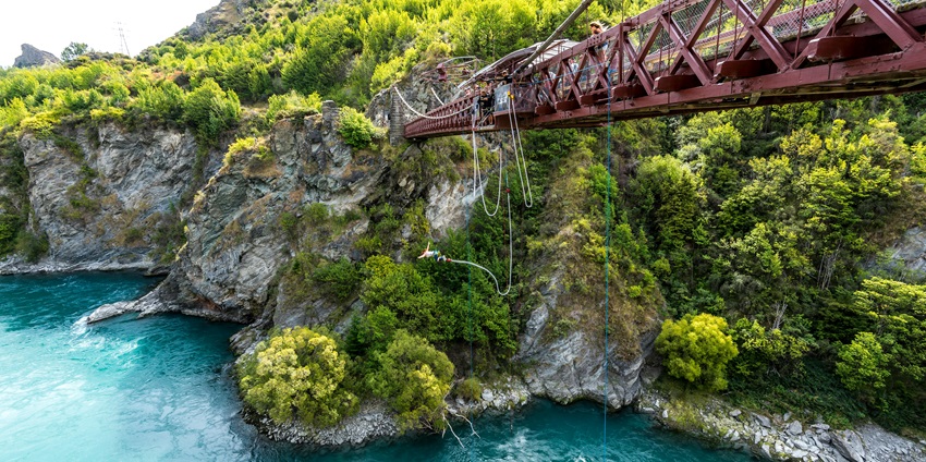 A stunning view of a person harnessed with a rope jumping from a cliff during the daytime.