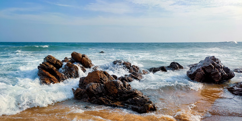An image of a beautiful view of a brown rocky shore under a blue sky during the daytime.
