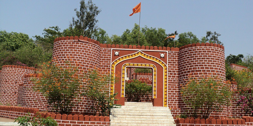 Ponda fort with stone walls and towers, surrounded by greenery and blue sky.