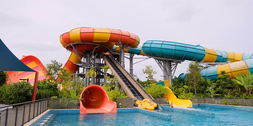 A picture of a water slide finishing in a big swimming pool at a water park