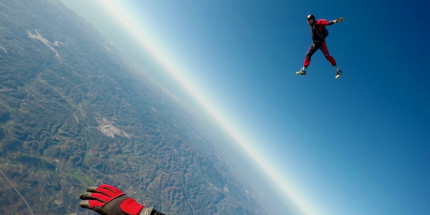 A stunning view of a person in red suit enjoying skydiving in the air during the daytime.