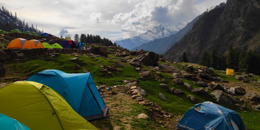 A beautiful view of Kheer Ganga trekking site with multiple green mountains surrounding it