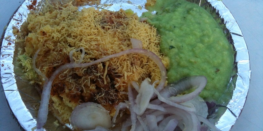 A view of a plate with hot and savoury Locho served with chutneys and garnishes for a kick.