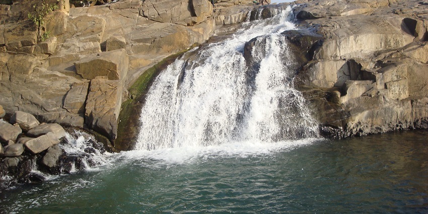 A wide-angle shot of a waterfall, with the river flowing into a serene pool at the base of the falls