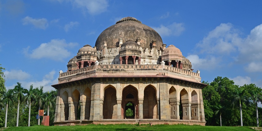 Image of a fort ruin in Lodhi Garden surrounded by lush green grass and clear blue sky