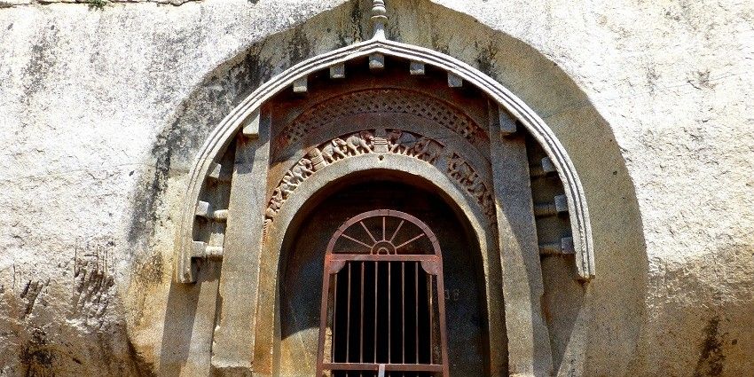 Entrance to the caves, carved into a hillside, with rocky steps leading up to the ancient Buddhist site
