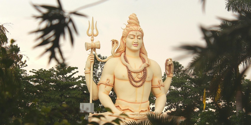 Black stone statue of lord Shiva and Goddess Parvati smeared in orange vermilion
