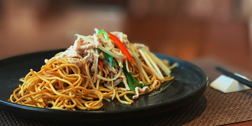 Image of a plate of noodles served in a black plate - explore the best food in Somnath