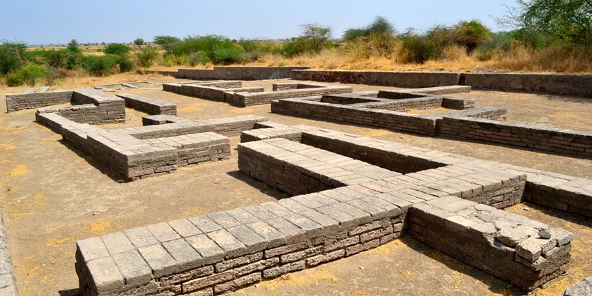 Image of an ancient site at Lothal and ruins surrounding lush green trees and grass