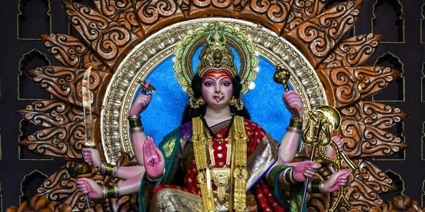 A statue of Maa Durga Devi sitting elegantly on a golden throne with intricate details.