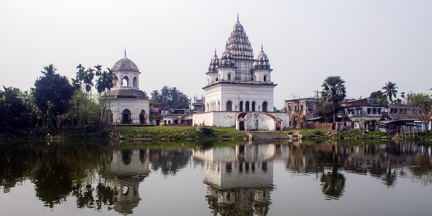A picture of a Shiv temple taken from across a water body with its reflection forming in the water