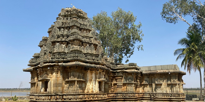Mahanandi temple with intricate carvings, set against lush green hills under a cloudy sky