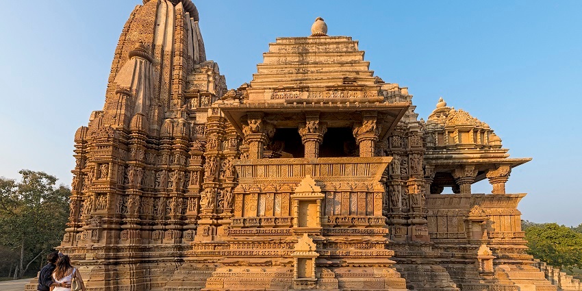 Ornate temple shrine with intricate carvings and statues, set against a cloudy sky in a serene setting.