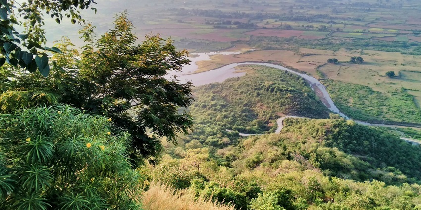 A breathtaking view of Maihar with lush greenery and a stream of water passing through.