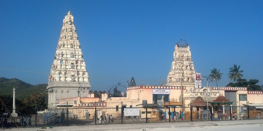 Exterior view of Male Mahadeshwara Temple surrounded by hills and greenery.