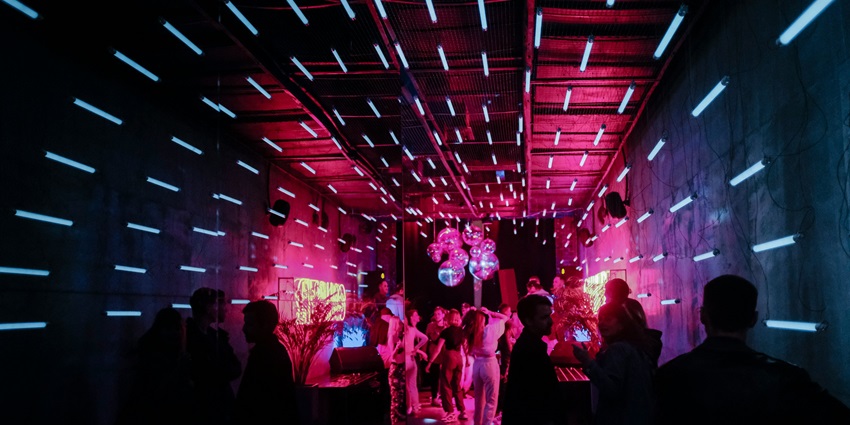 An inside view of club Mambo’s featuring glistening neon lights and people dancing.