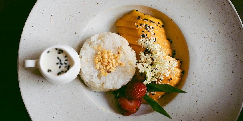 A view of Mamidikaya Pulihora featuring sticky rice, freshly cut mangoes, and chutney.