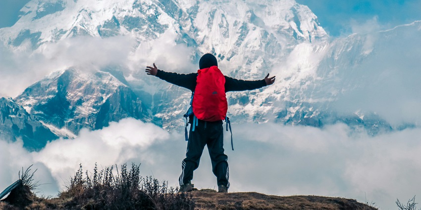 Image of a man enjoying the scenic view of snow-covered mountains and trekking.