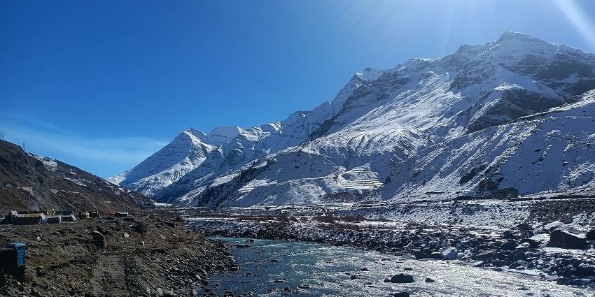 Image of Manali snow covered mountains and ray of sun shining on top under clear blue sky