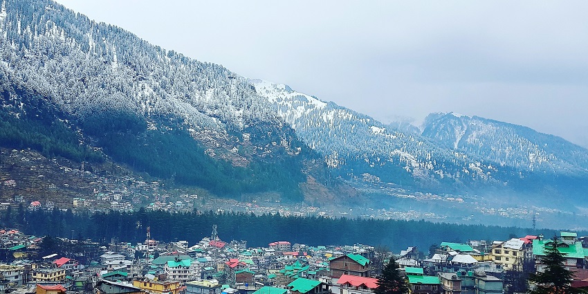 A vibrant view of Manali city, popular in hill stations near Gurugram, surrounded by majestic mountains and lush greenery.