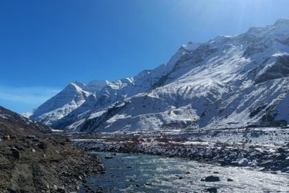 Snow-capped mountains in Manali, showcasing a stunning winter landscape under a clear blue sky.