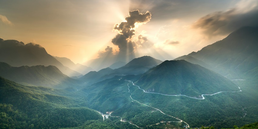 Sunrise beams illuminate green mountains, reminiscent of the stunning Mandhata Hill.