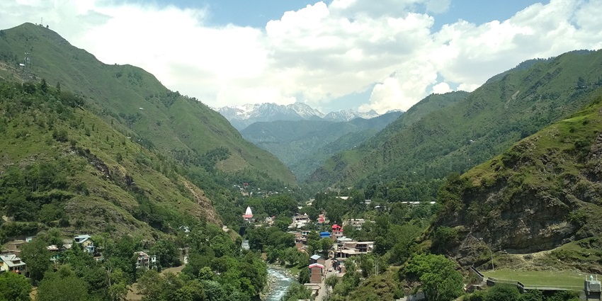 A panoramic view of the town of Mandi, nestled among hills under a clear blue sky.