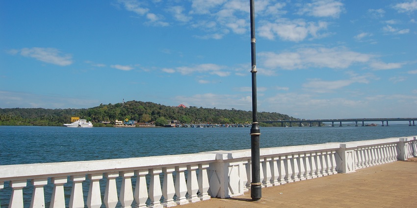 A bridge overlooking the tranquil Mandovi River featuring shimmering blue water.