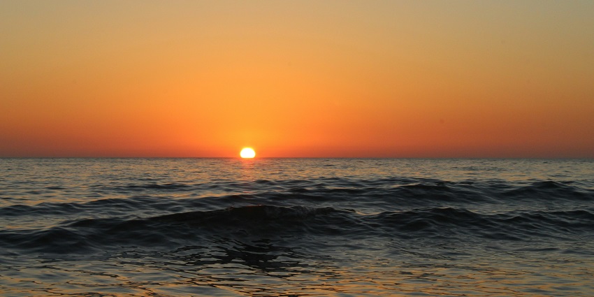 Picturesque view of a sunset at Mandi beach with tranquil water and colourful sky
