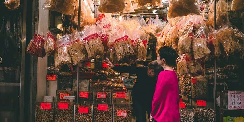 A couple spending the evening at a street food market, browsing meal options from a food vendor.