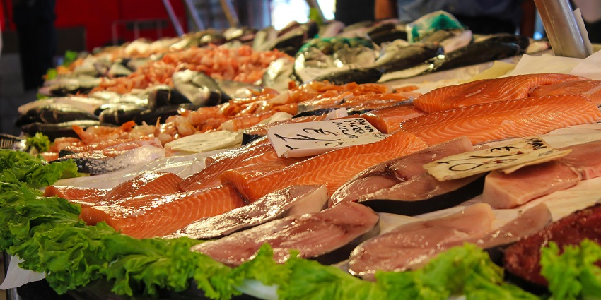 Image of a fish market - salmon fish displayed for sale and local vegetables in a market