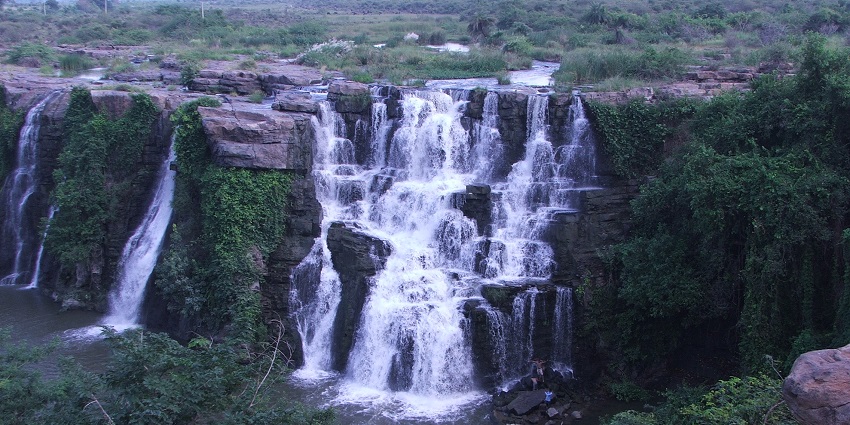An aerial picture of a waterfall cascading down a rocky hill and forming a puddle at the base.