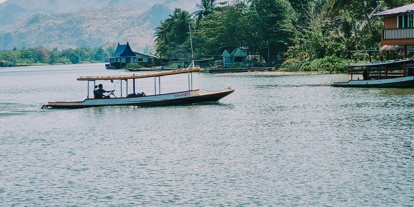 A glimpse of a person sailing a boat on the shimmering waters of the Mekong River.