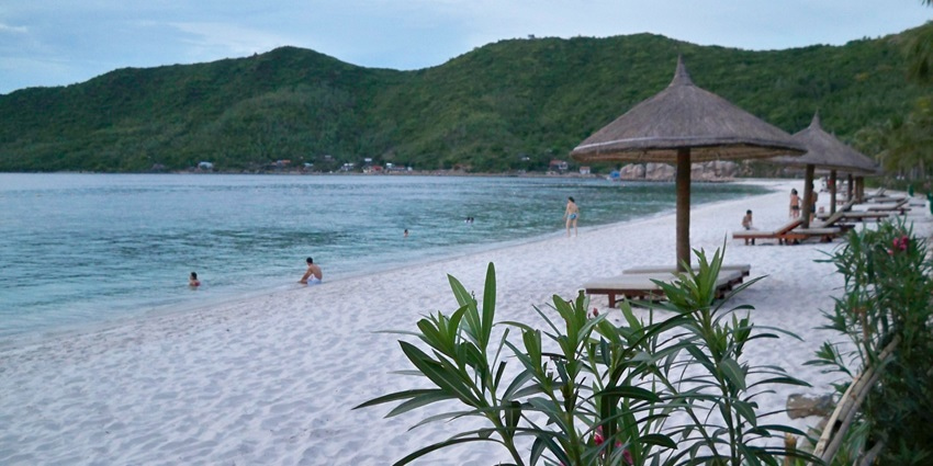 A picture of a beach during twilight with stunning grey sand and turquoise waters