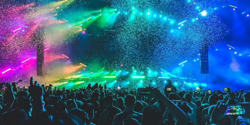 A glimpse of people enjoying and dancing in a club adorned with colourful neon lights.