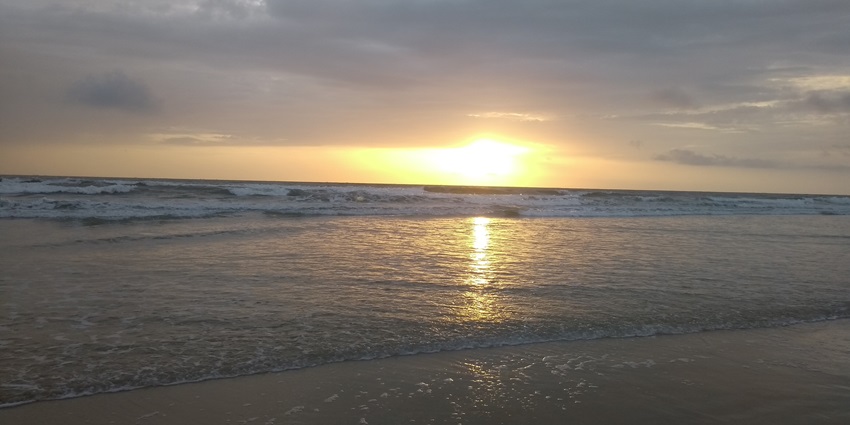 A calming sunset at a beach in Goa with orange hues covering the blue waters of the sea