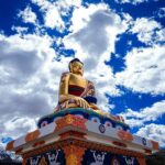 A breathtaking view of a statue of Buddha on a cliff under dense clouds during the day.