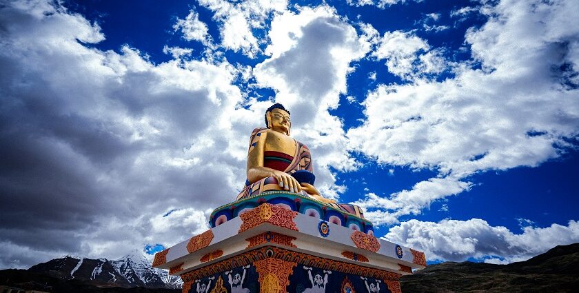 A breathtaking view of a statue of Buddha on a cliff under dense clouds during the day.