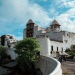 The verdant greenery surrounding the Sajjangarh Fort with people during the daytime.