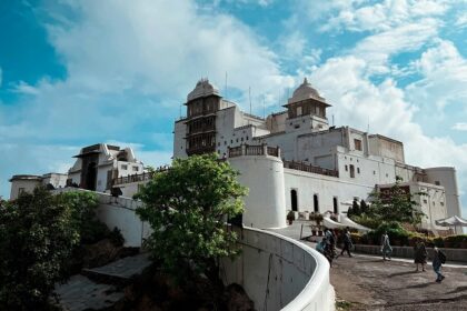 The verdant greenery surrounding the Sajjangarh Fort with people during the daytime.